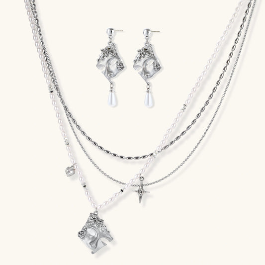 Ornate silver-toned masquerade mask jewelry set featuring rhinestone details and pearl drop earrings on white background.