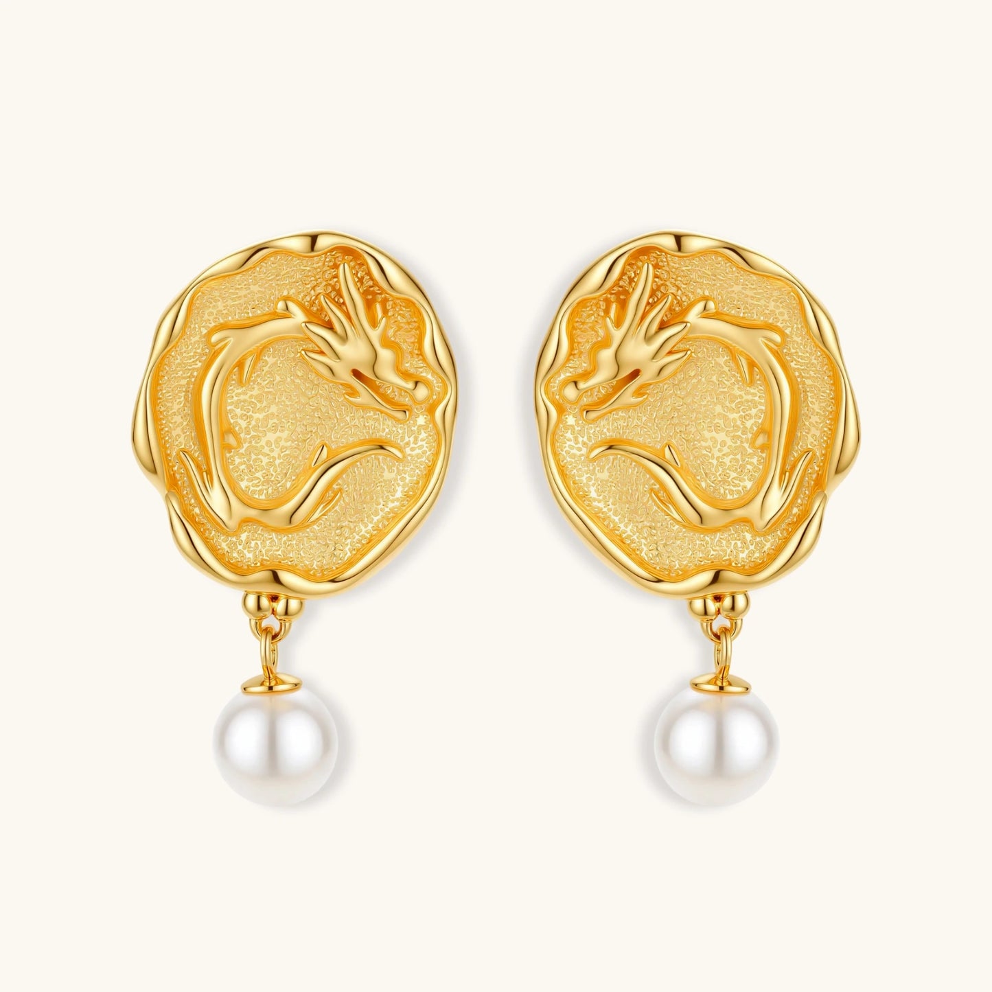 Ornate gold-plated dragon medallion earrings with white shell pearl drops on beige background, featuring detailed Chinese motifs.