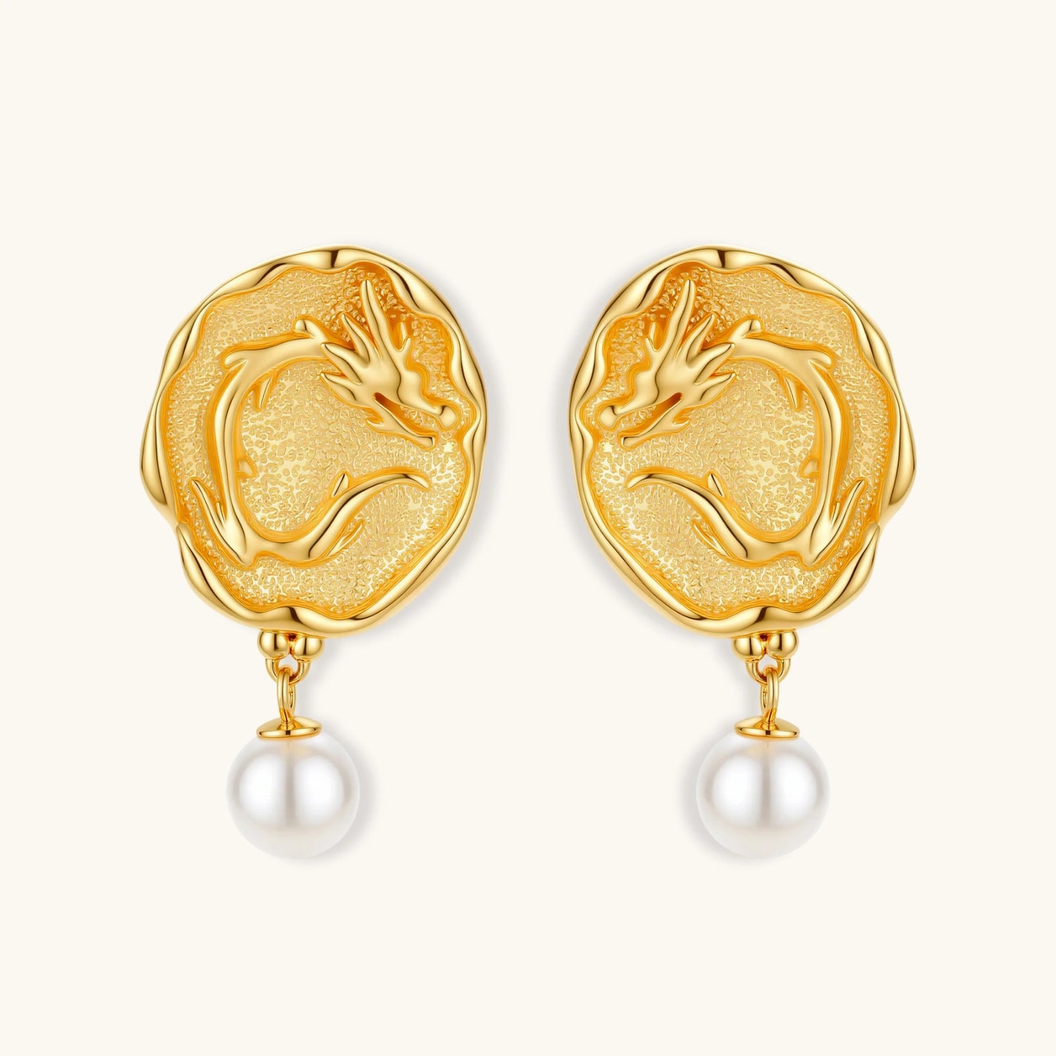 Ornate gold-plated dragon medallion earrings with white shell pearl drops on beige background, featuring detailed Chinese motifs.