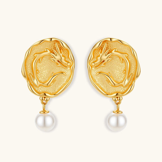 Ornate gold-plated dragon medallion earrings with white shell pearl drops on beige background, featuring detailed Chinese motifs.