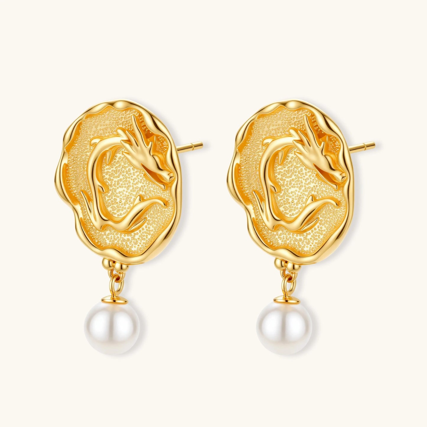 Ornate gold-plated dragon medallion earrings with white shell pearl drops on beige background, featuring detailed Chinese motifs.