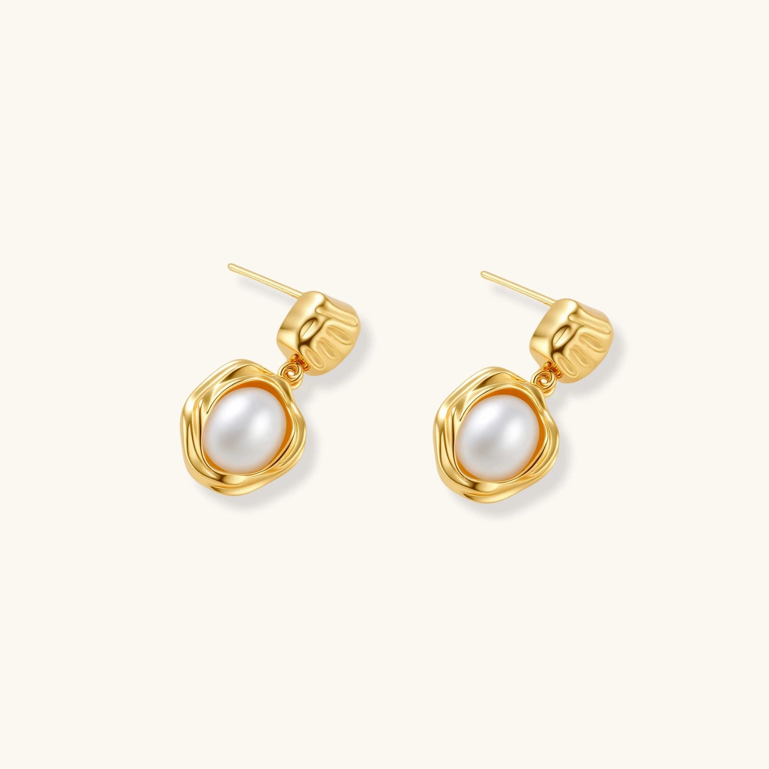 Gold-plated textured stud earrings with white freshwater pearl drops against cream background, showing organic rippled design