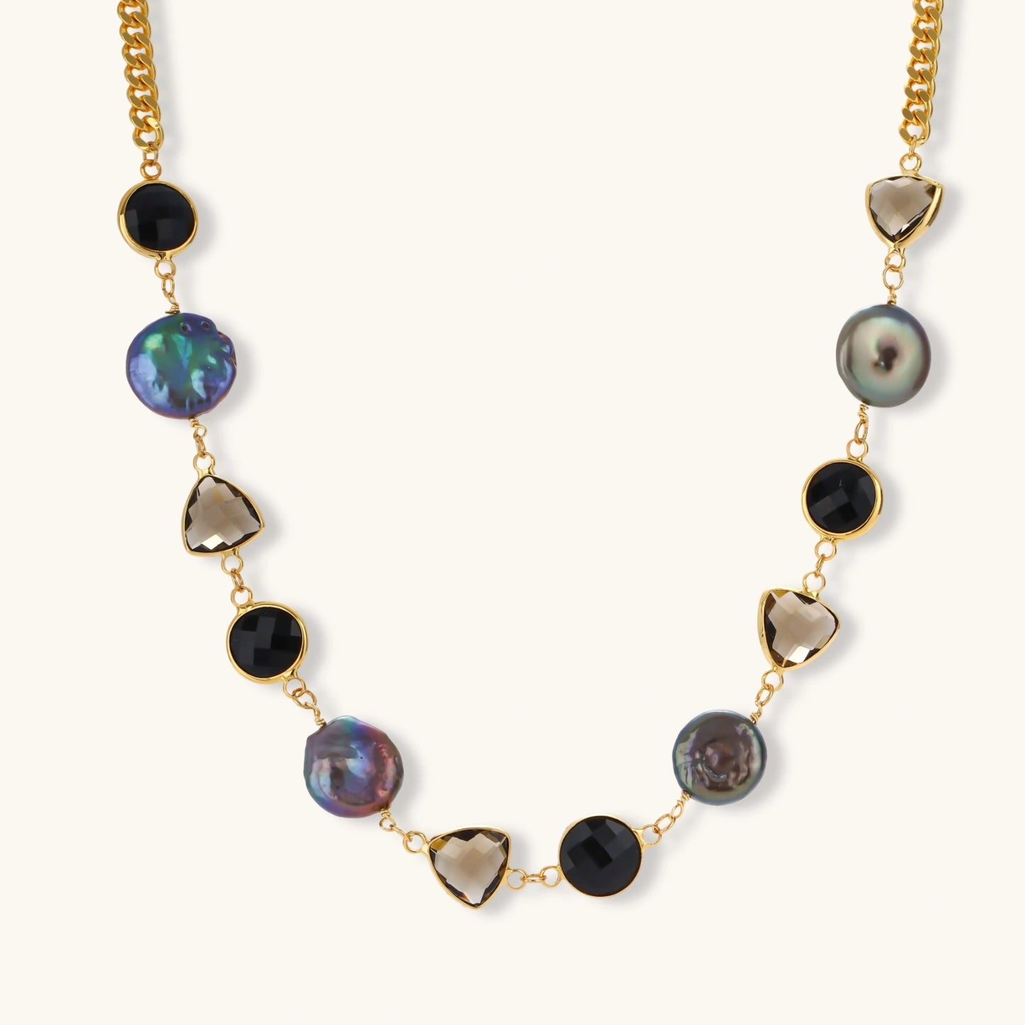 18k gold-plated chain necklace featuring lustrous baroque pearls, black onyx rounds, and smoky quartz triangular stones on white background.