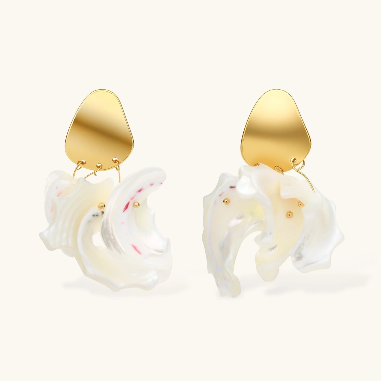 Gold-plated copper earrings with organic pebble studs and natural shell drops on cream background.