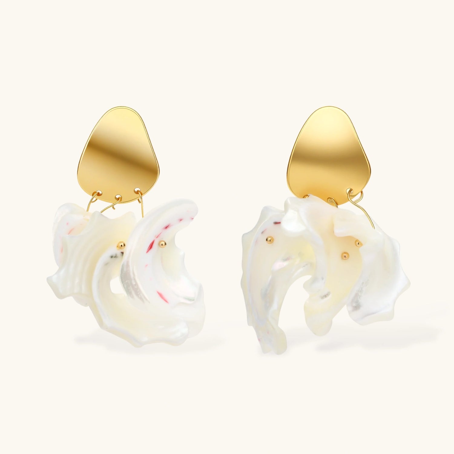 Gold-plated copper earrings with organic pebble studs and natural shell drops on cream background.