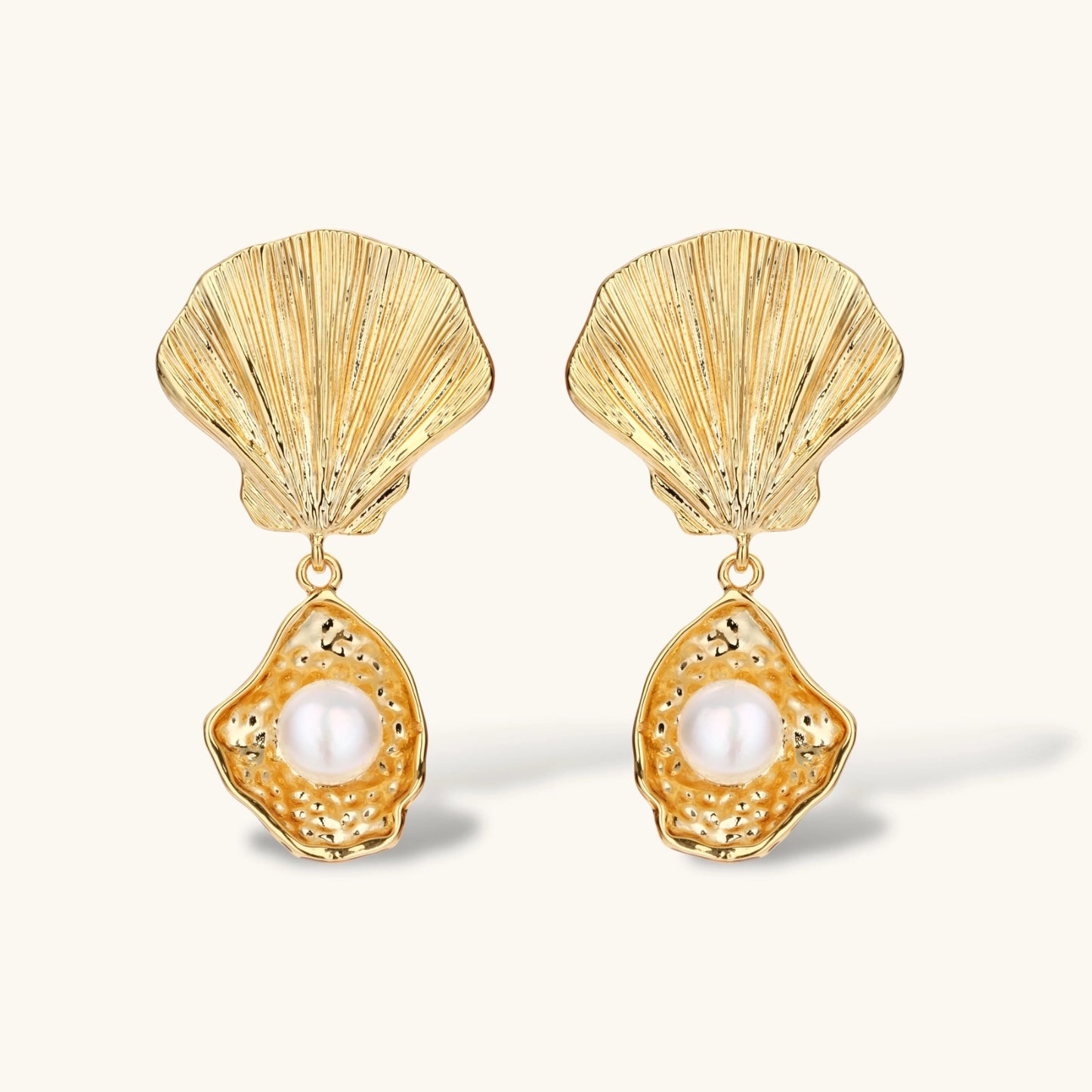 Gold shell-shaped drop earrings with scallop tops and oyster bottoms featuring round freshwater pearls on white background.